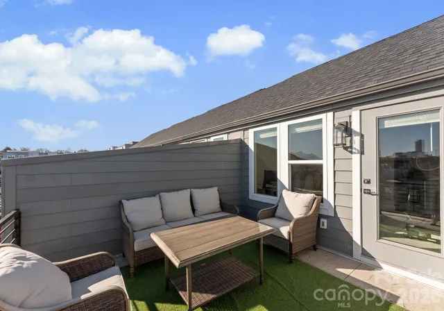 a roof deck with a table and chairs and potted plants