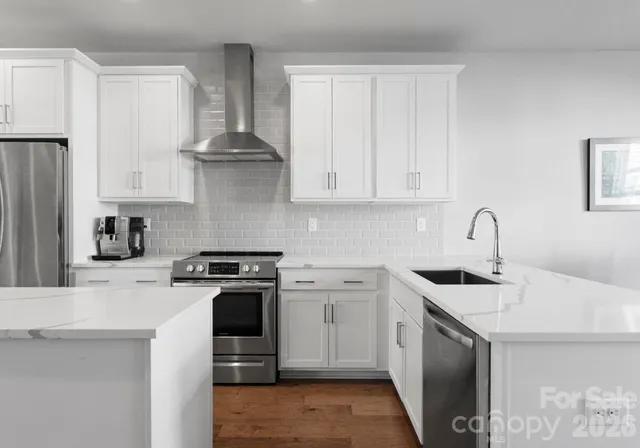 a kitchen with stainless steel appliances granite countertop a stove and white cabinets