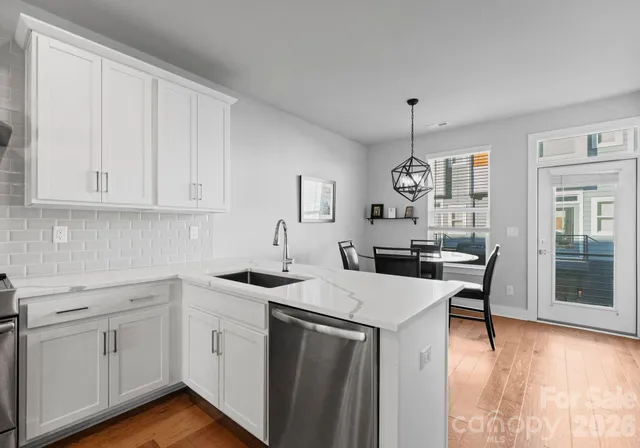 a kitchen with a sink dishwasher a stove a dining table and chairs