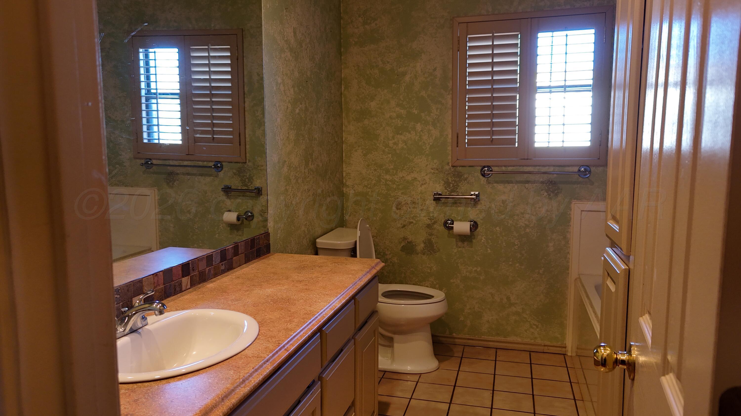 2100 13th Avenue Canyon, TX 79015 - Photo 6 of 11 a bathroom with a sink toilet a mirror and shower
