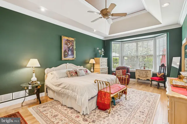 a bedroom with a bed a large window and wooden floor