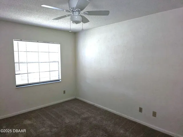 an empty room with a window and a fan