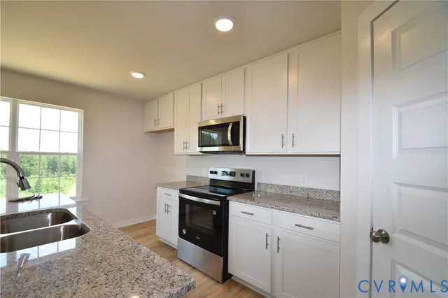 a kitchen with granite countertop a stove sink and microwave