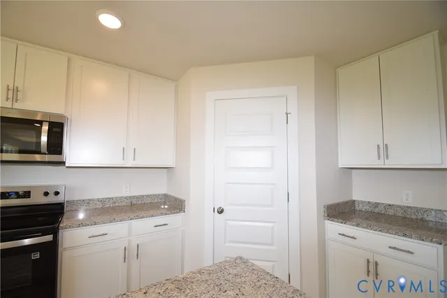 a kitchen with granite countertop white cabinets and stainless steel appliances