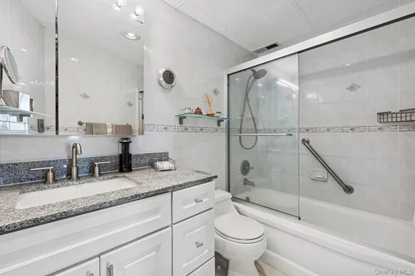 a bathroom with a granite countertop sink mirror toilet and bathtub