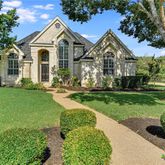 a view of a white house next to a yard with big trees