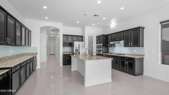 a kitchen with stainless steel appliances kitchen island granite countertop a refrigerator and a stove top oven