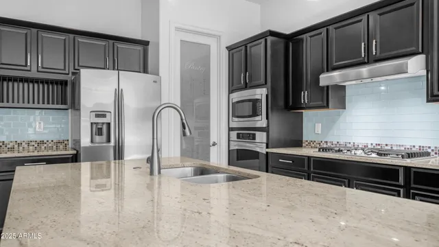 a kitchen with granite countertop a refrigerator and a stove top oven