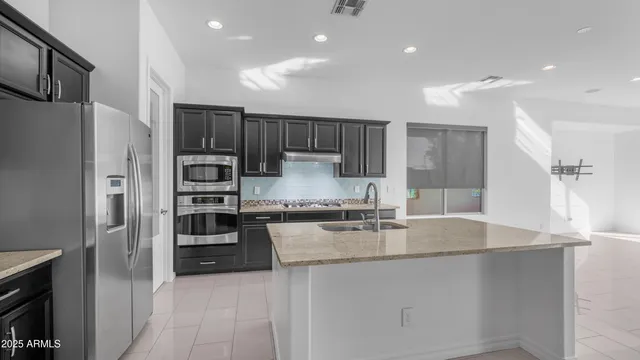 a kitchen with stainless steel appliances granite countertop a refrigerator a sink a stove and oven