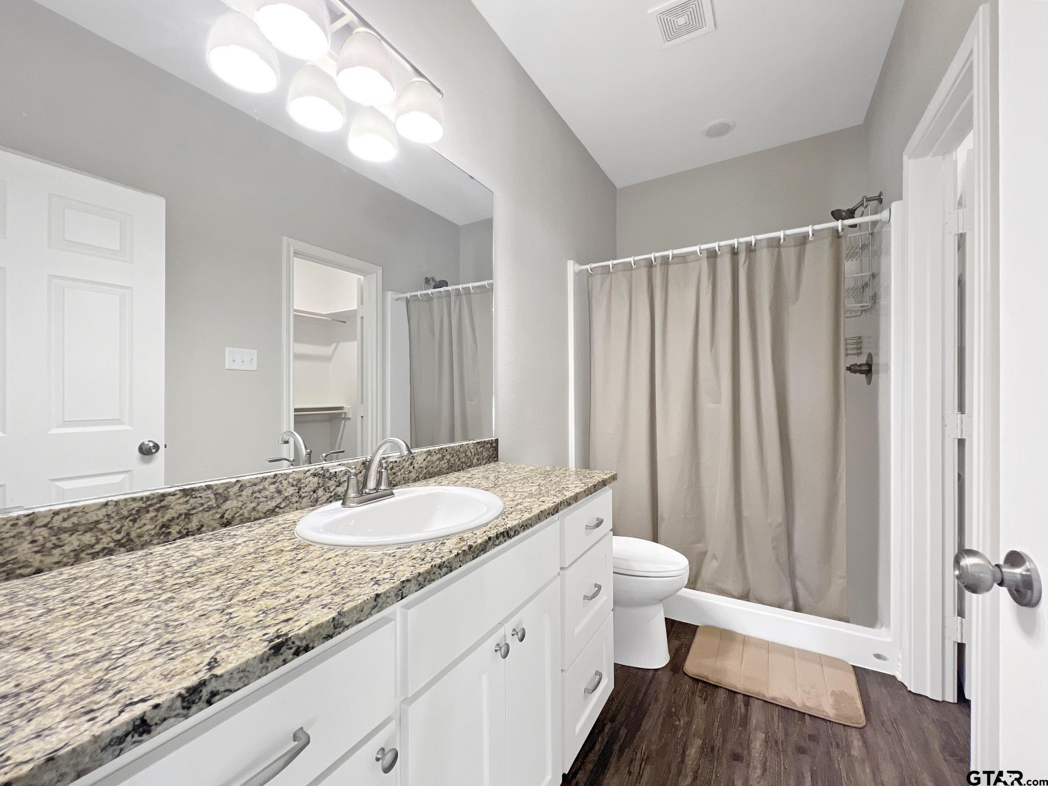 107 Short Street Gilmer, TX 75645 - Photo 11 of 26 a bathroom with a granite countertop double vanity sink and a mirror