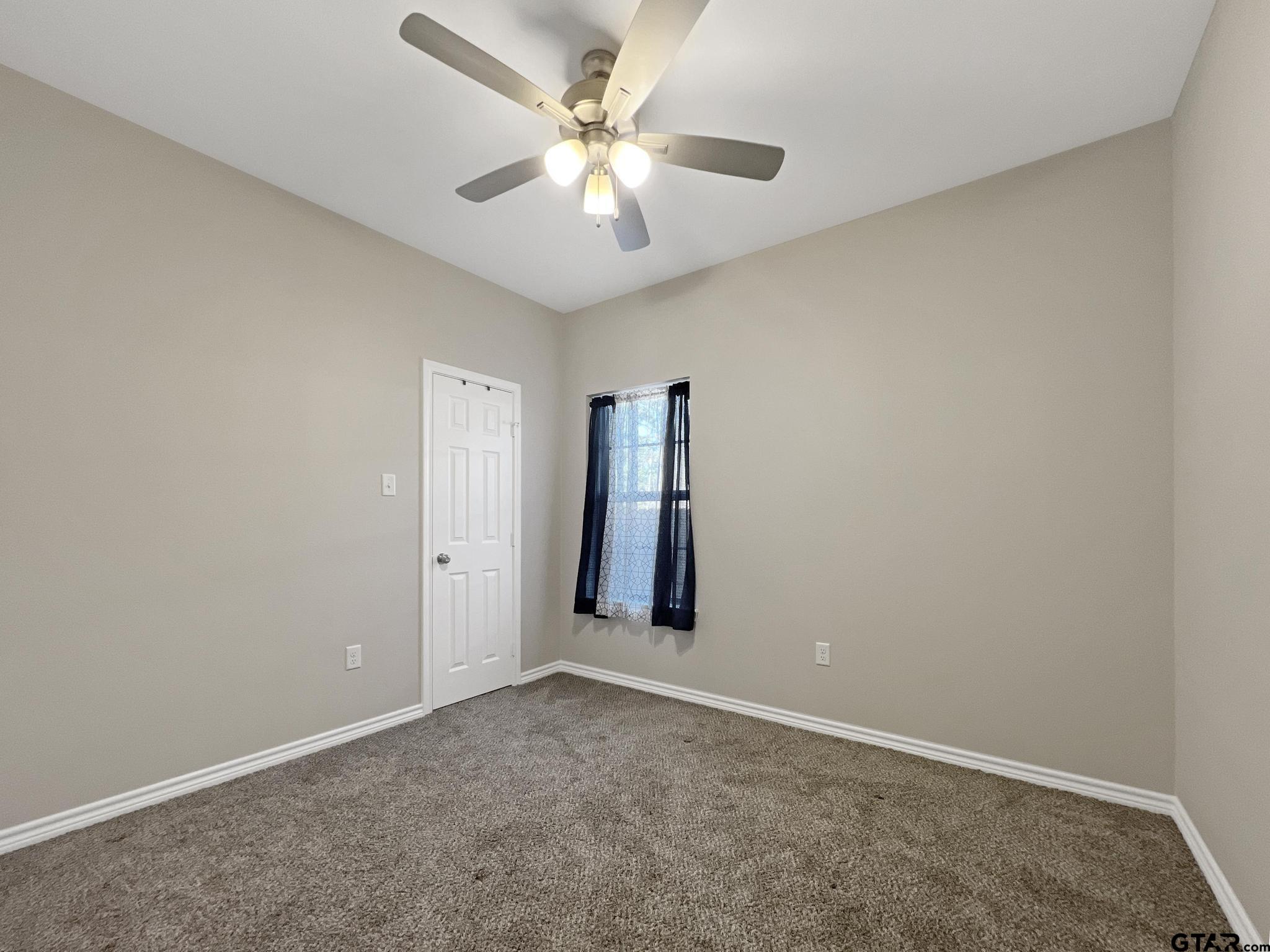 107 Short Street Gilmer, TX 75645 - Photo 14 of 26 an empty room with windows and fan