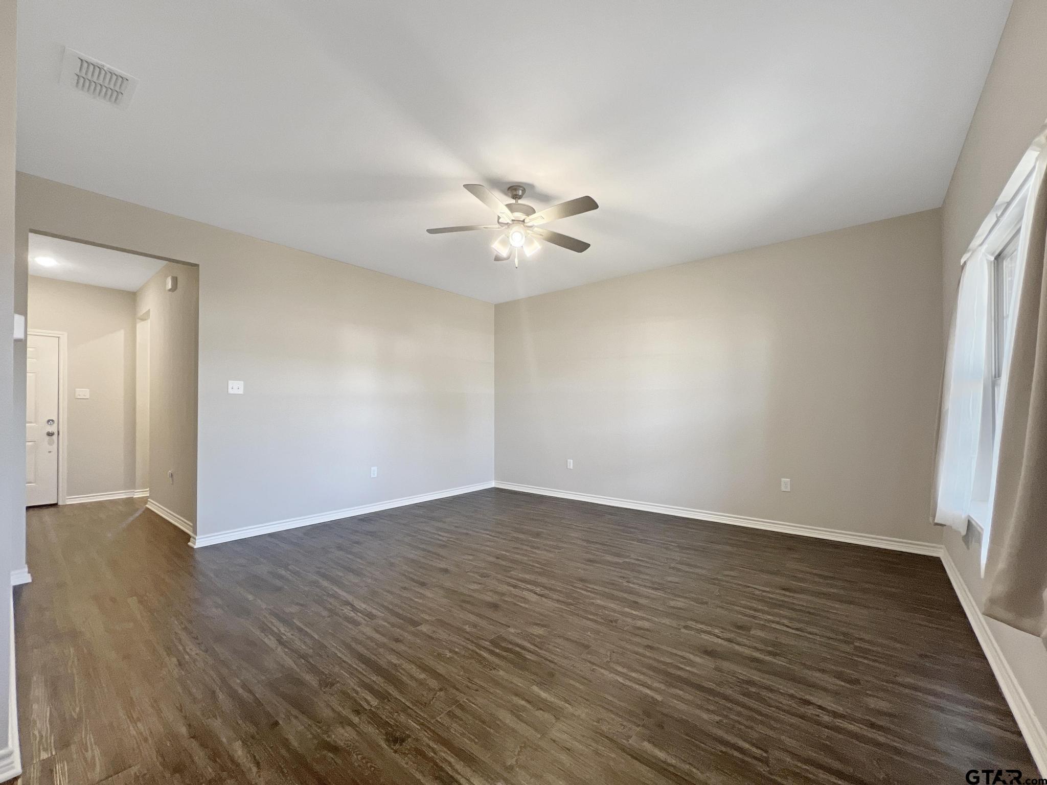 107 Short Street Gilmer, TX 75645 - Photo 4 of 26 wooden floor in an empty room with a window
