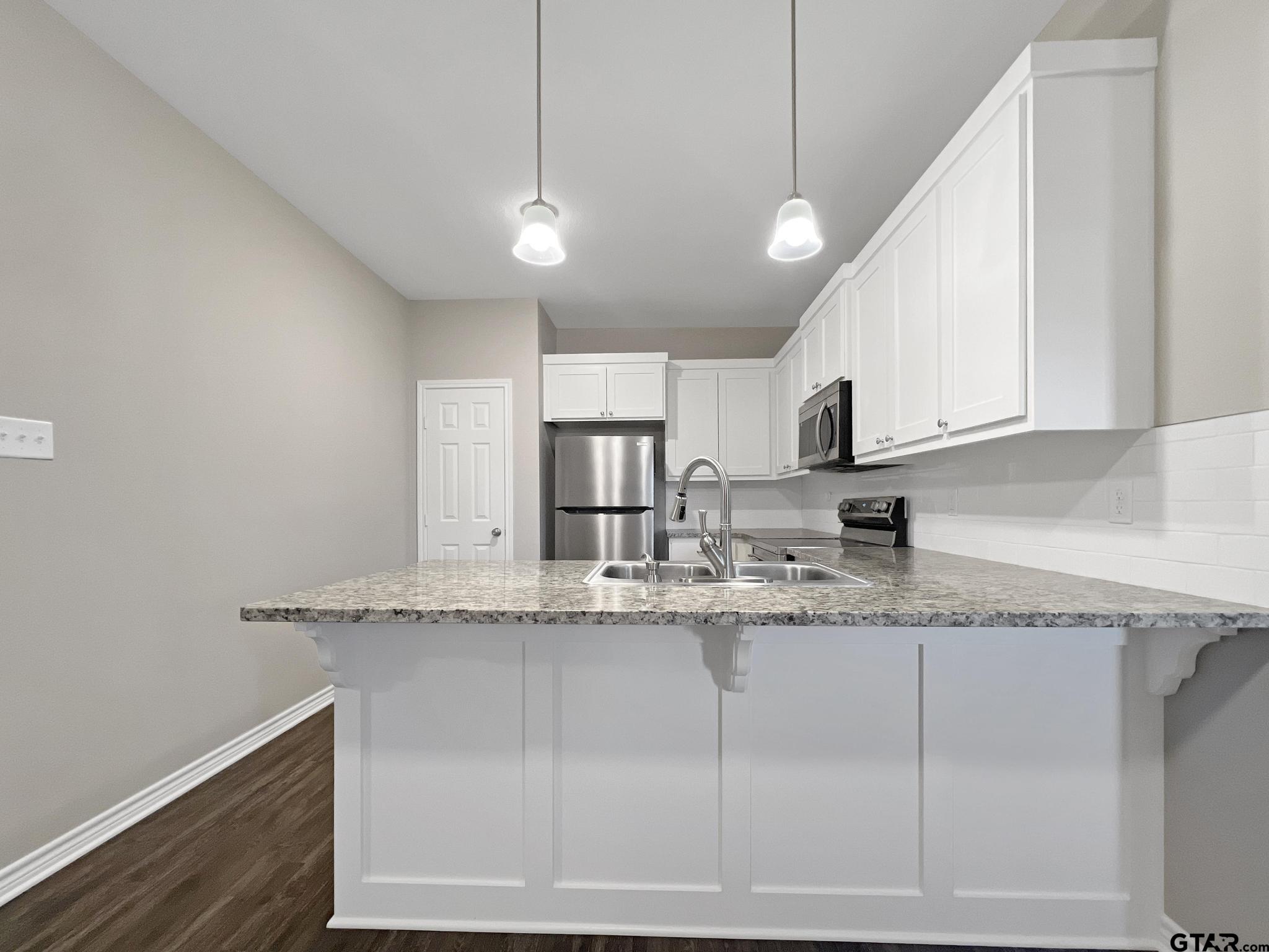 107 Short Street Gilmer, TX 75645 - Photo 5 of 26 a kitchen with stainless steel appliances granite countertop a sink a stove and cabinets