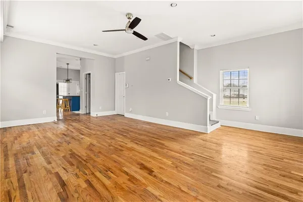 a view of empty room with wooden floor and fan