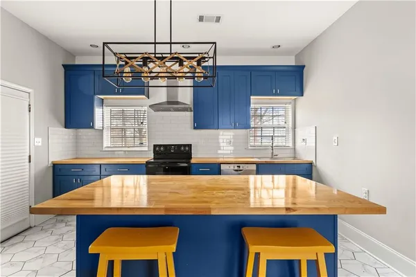 a kitchen with stainless steel appliances kitchen island a table chairs in it and wooden floors