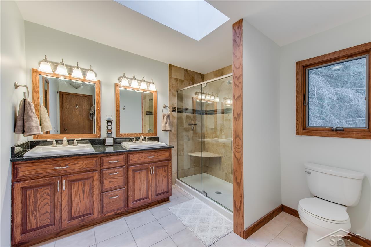 3201 Pomranky Road Midland, MI 48640 - Photo 12 of 29 This is the master bath. Notice the indulgent finishes including glass shower wall, his and hers sinks and custom tile.