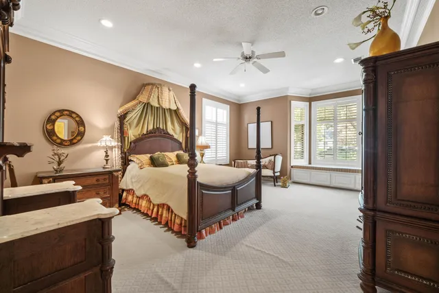 a spacious bedroom with a bed a dresser next to a window