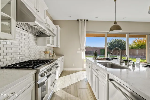 a kitchen with stainless steel appliances granite countertop a stove a sink and a refrigerator