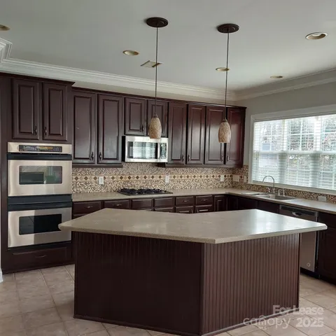 a kitchen with kitchen island granite countertop a sink a stove and cabinets