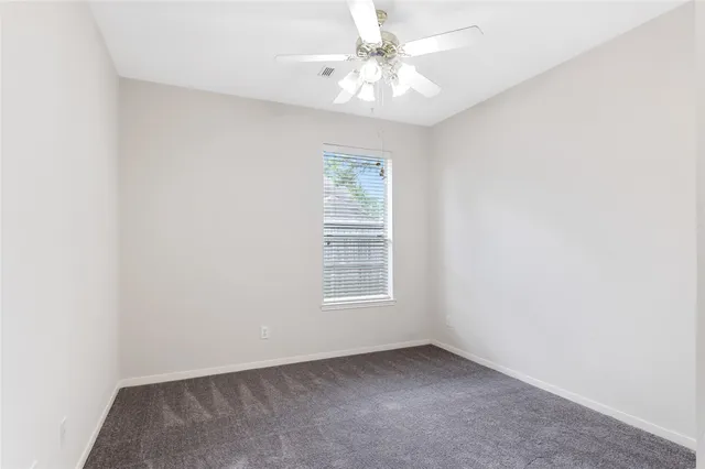 an empty room with windows and ceiling fan