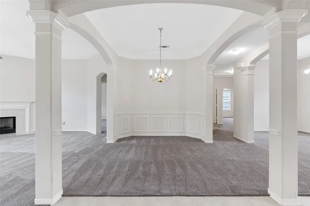 a view of an empty room with chandelier fan and wooden floor