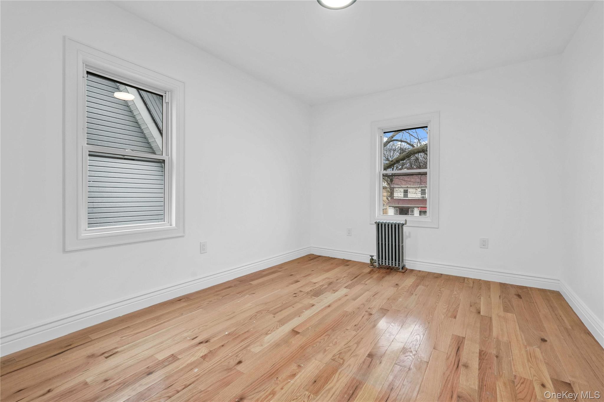 21432 112th Road Queens, NY 11429 - Photo 9 of 18 Empty room featuring radiator and light wood-type flooring