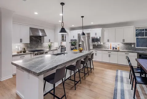 a kitchen with stainless steel appliances granite countertop a stove a sink a microwave a island with a dining table and chairs