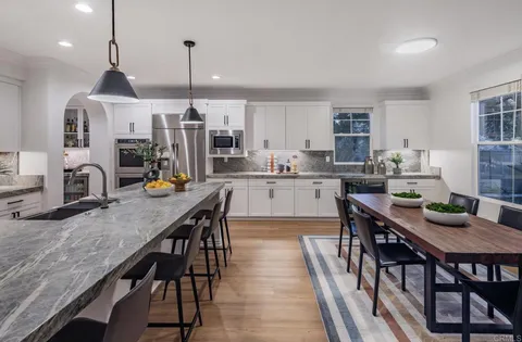 a kitchen with stainless steel appliances granite countertop a kitchen island a stove a table and chairs