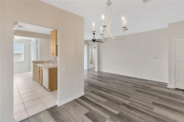 an empty room with a chandelier fan and windows