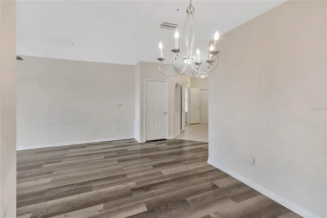 a view of empty room with wooden floor and ceiling fan