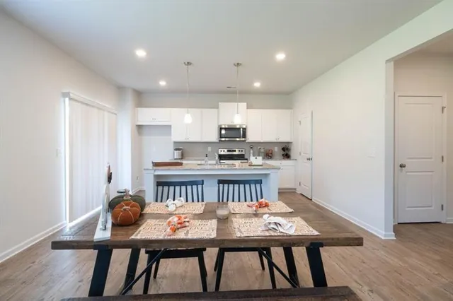 a kitchen with a table chairs a sink dishwasher refrigerator and cabinets