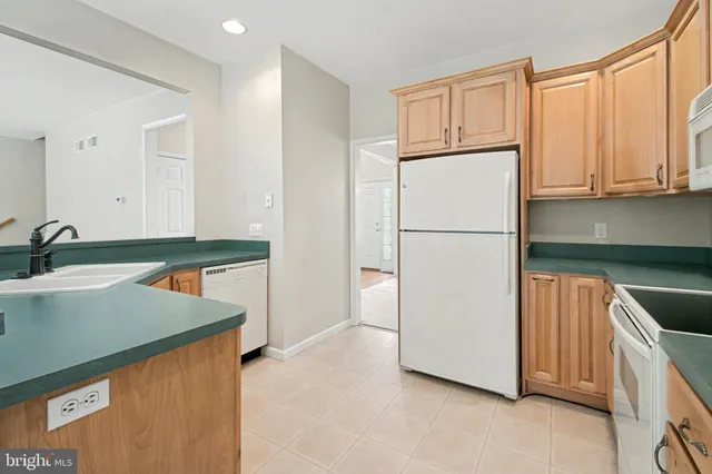 a kitchen with stainless steel appliances a refrigerator a sink and white cabinets