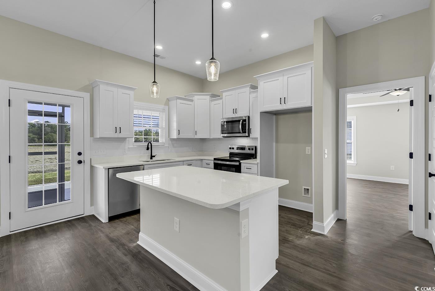 3255 Red Bluff Road Loris, SC 29569 - Photo 14 of 38 Kitchen with a kitchen island, pendant lighting, white cabinets, stainless steel appliances, and light stone counters