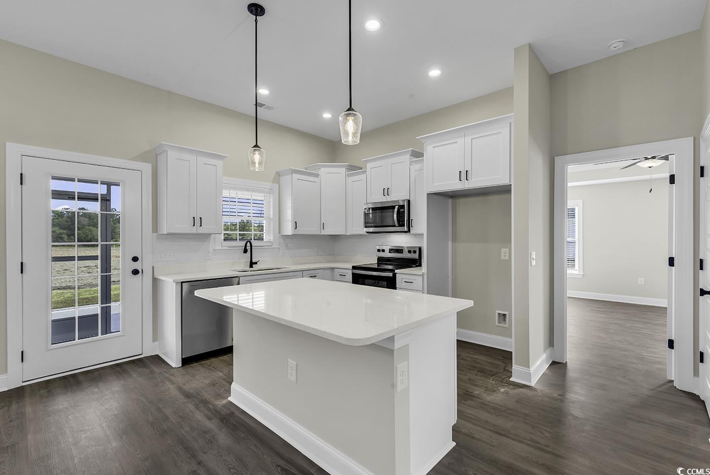 3255 Red Bluff Road Loris, SC 29569 - Photo 15 of 38 Kitchen with a center island, white cabinets, stainless steel appliances, decorative light fixtures, and dark wood finished floors