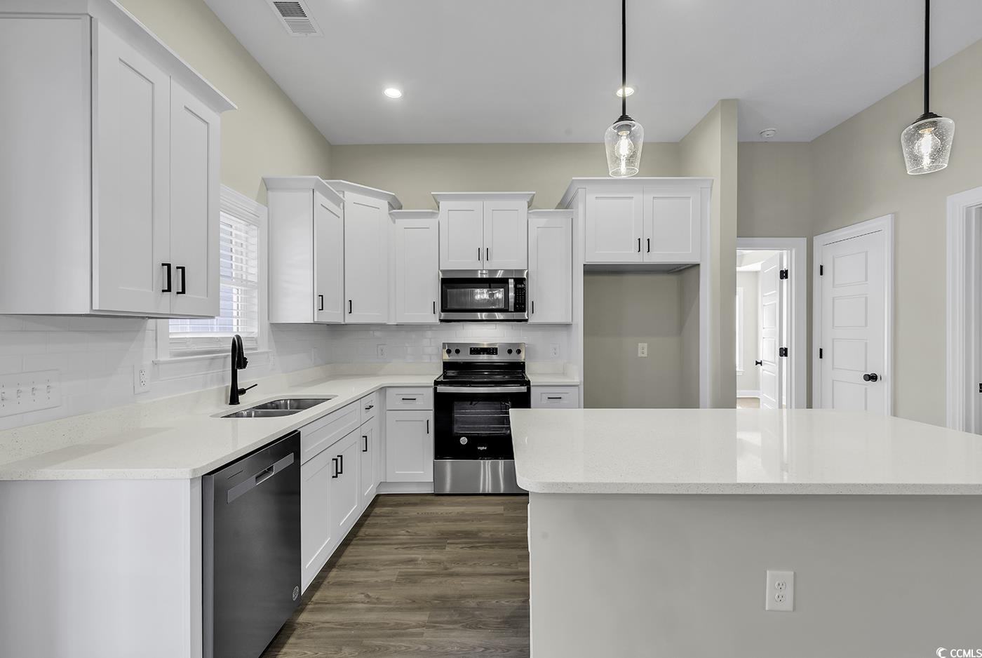 3255 Red Bluff Road Loris, SC 29569 - Photo 16 of 38 Kitchen with appliances with stainless steel finishes, hanging light fixtures, white cabinetry, backsplash, and light stone countertops