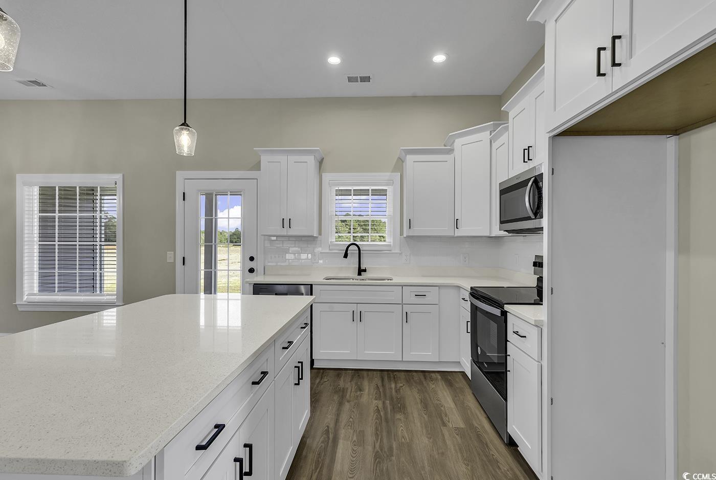 3255 Red Bluff Road Loris, SC 29569 - Photo 19 of 38 Kitchen featuring a kitchen island, stainless steel appliances, pendant lighting, white cabinetry, and tasteful backsplash