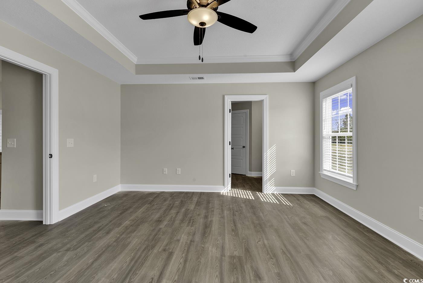 3255 Red Bluff Road Loris, SC 29569 - Photo 34 of 38 Spare room featuring a tray ceiling, dark wood-style flooring, ornamental molding, and a ceiling fan