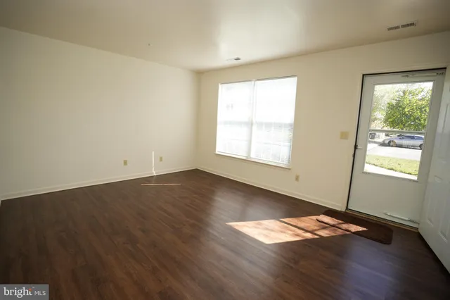 an empty room with wooden floor and windows