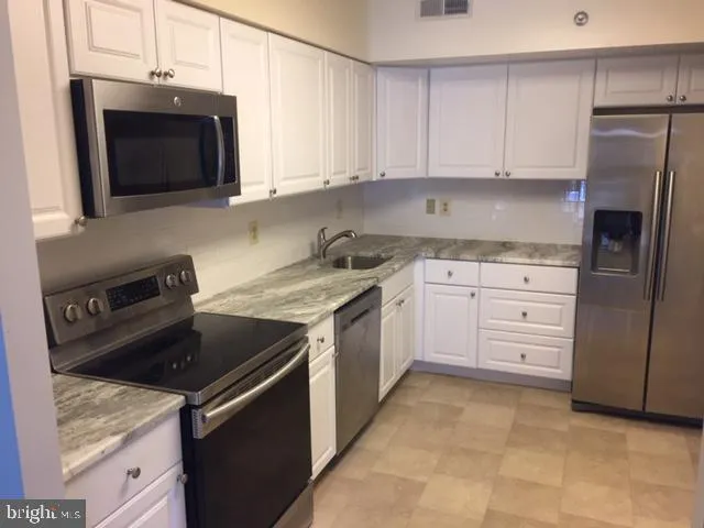 a kitchen with stainless steel appliances granite countertop a stove a microwave and a refrigerator