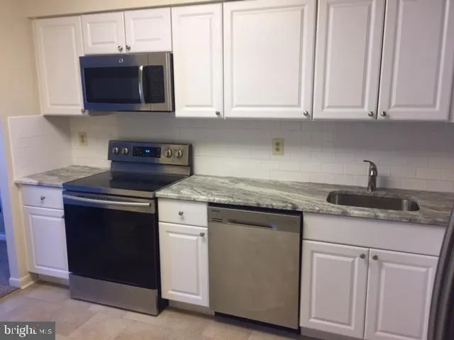 a kitchen with granite countertop white cabinets and a stove top oven