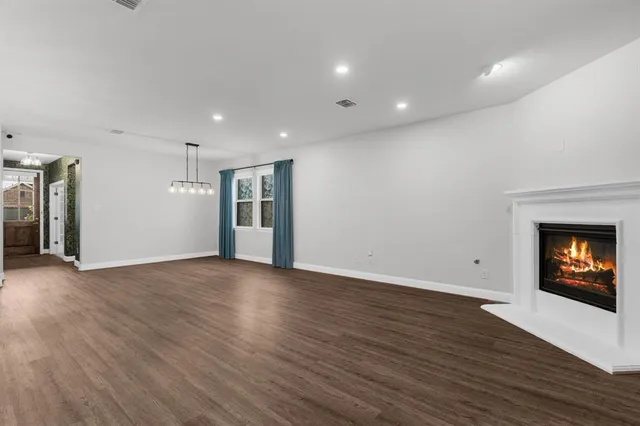 a view of an empty room with wooden floor fireplace and a window
