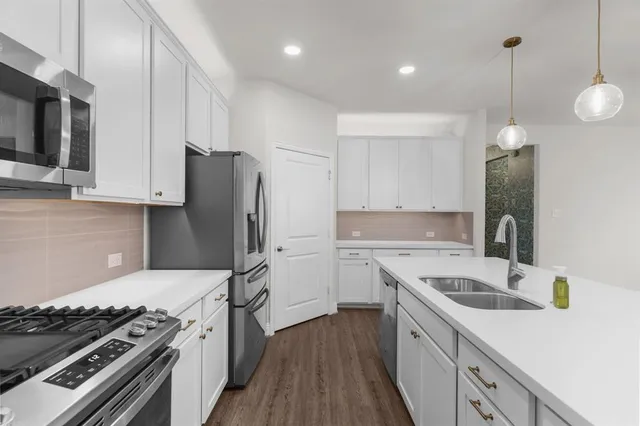 a kitchen with stainless steel appliances granite countertop a sink a stove and a refrigerator