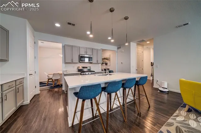 a kitchen with stainless steel appliances a dining table chairs stove refrigerator and cabinets