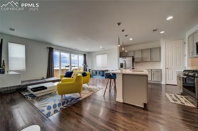 a living room with furniture kitchen and a wooden floor