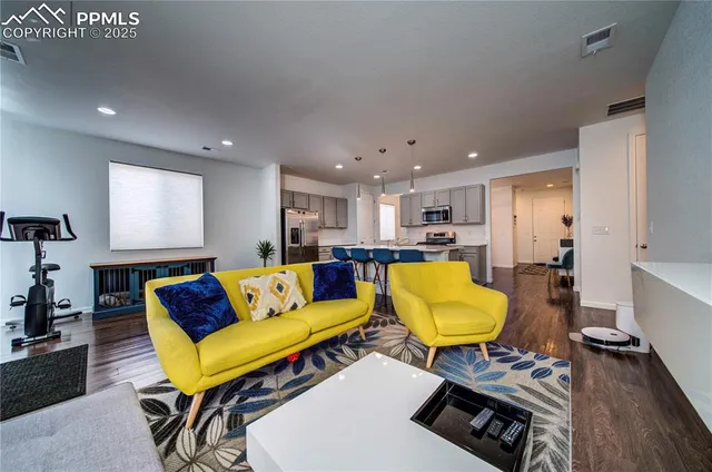 a living room with furniture and a dining table with wooden floor