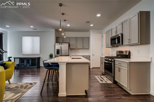 a kitchen with stainless steel appliances kitchen island granite countertop a stove a sink a refrigerator and a microwave