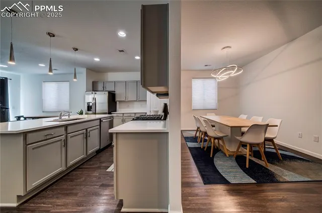 a kitchen with stainless steel appliances kitchen island granite countertop a table chairs sink and cabinets