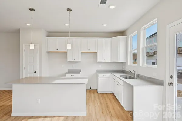 a kitchen with kitchen island a sink a stove a refrigerator and white cabinets