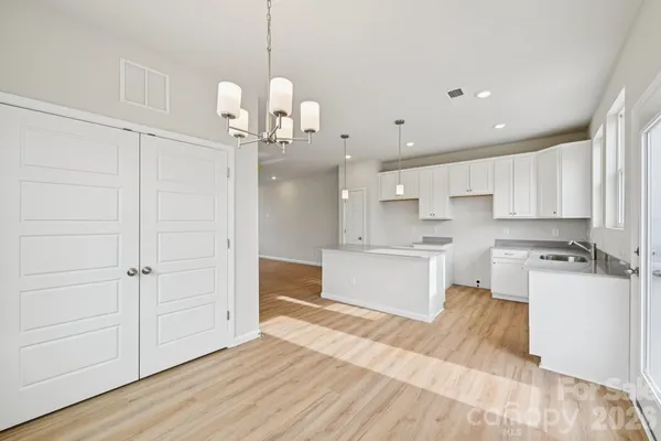 a large kitchen with kitchen island a stove a sink dishwasher a refrigerator and white cabinets with wooden floor