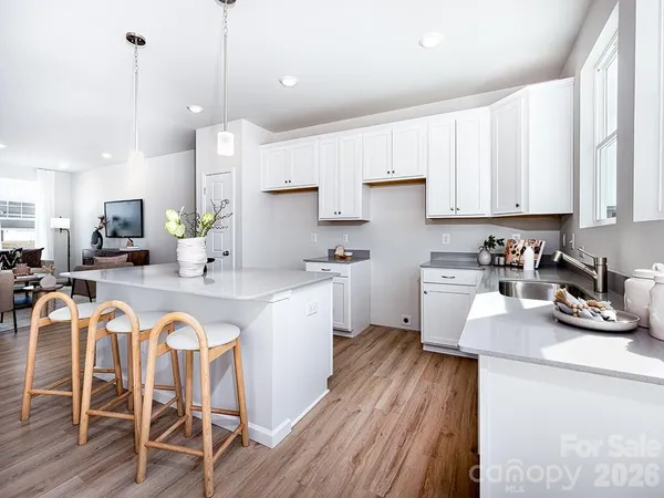 a kitchen with stainless steel appliances granite countertop a stove top oven a sink a dining table and chairs with wooden floor